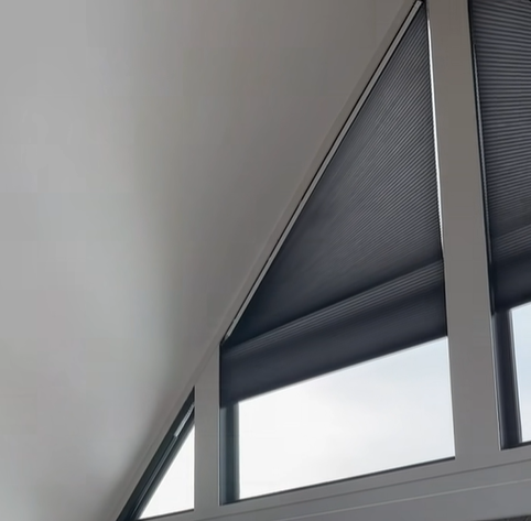Large angled honeycomb shade fitted under a wood A-frame ceiling with a mountain view